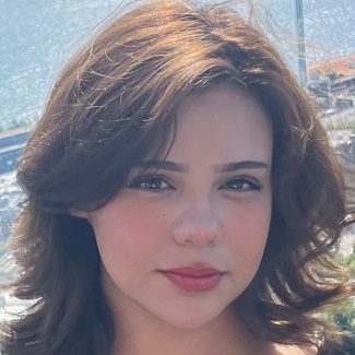 Close-up portrait of a person with short wavy hair, against a blurred background.