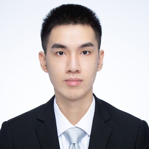 A formal portrait of a person wearing a black suit, white shirt, and looking directly at the camera with a neutral expression. The background is plain white.