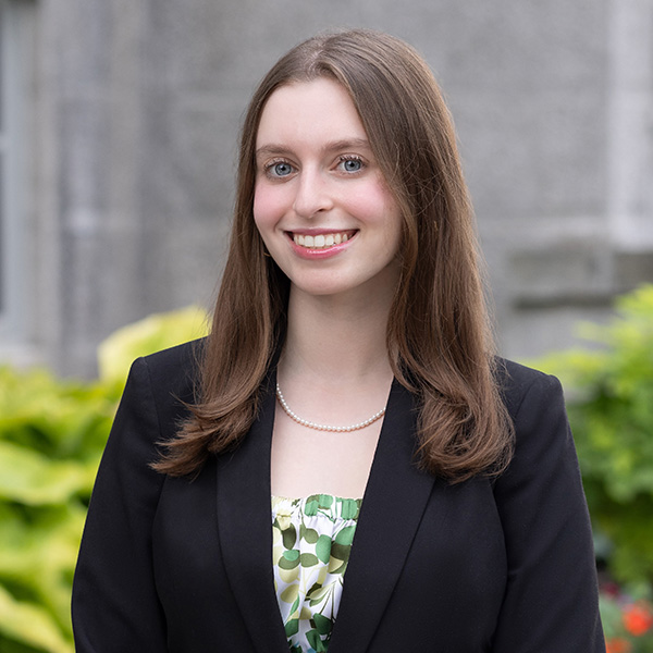 Young woman head and shoulders in a dark suit jacket and green floral blouse