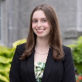 Young woman head and shoulders in a dark suit jacket and green floral blouse