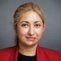 A person with blond hair pulled back wearing a red blazer with a black shirt.