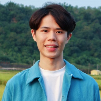 Person smiling in front of a natural landscape.