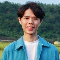 Person smiling in front of a natural landscape.