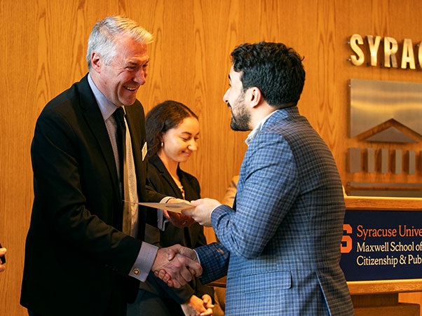 Tomás Olivier, assistant professor of public administration and international affairs, shakes hands with Dean David Van Slyke