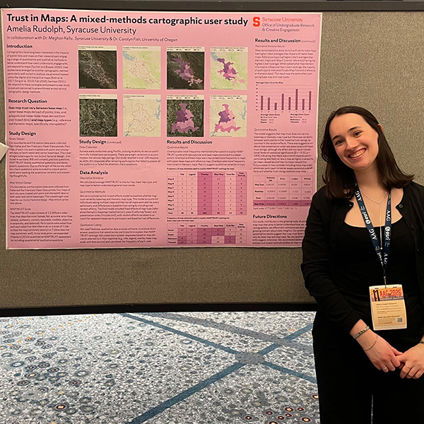 A person smiling beside a research poster titled "Trust in Maps: A mixed-methods cartographic study.”