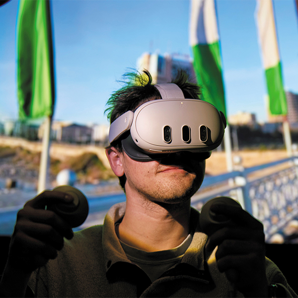 A student wears a virtual reality headset in front of a screen